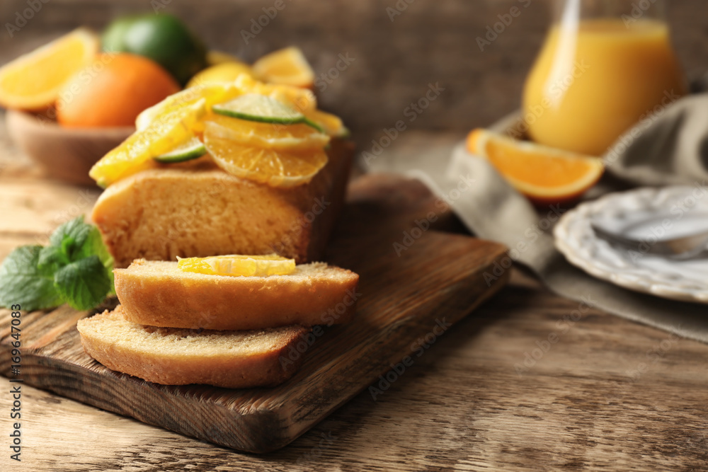 Cutting board with delicious sliced citrus cake and fruits on wooden table Cutting board with delicious sliced citrus cake and fruits on wooden table