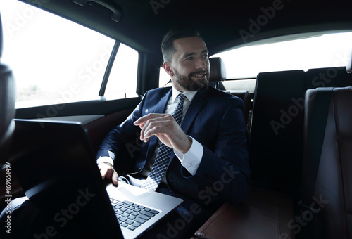 businessman sitting in the back seat in the car and pointing his