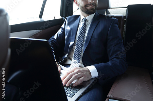 man with laptop sitting in the back seat in the car © ASDF