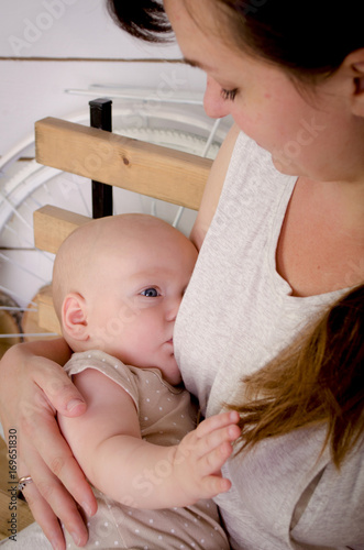 Obraz na płótnie Breastfeeding baby. Young mother holding her newborn child. Mom nursing baby. Woman and new born boy in white bedroom. w salonie