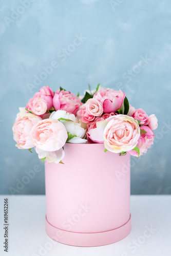 Flowers in round luxury present box. Bouquet of pink and white peonies in paper box. Mock-up of hat box of flowers with free copyspace for text. Interior decoration in in pastel colors.