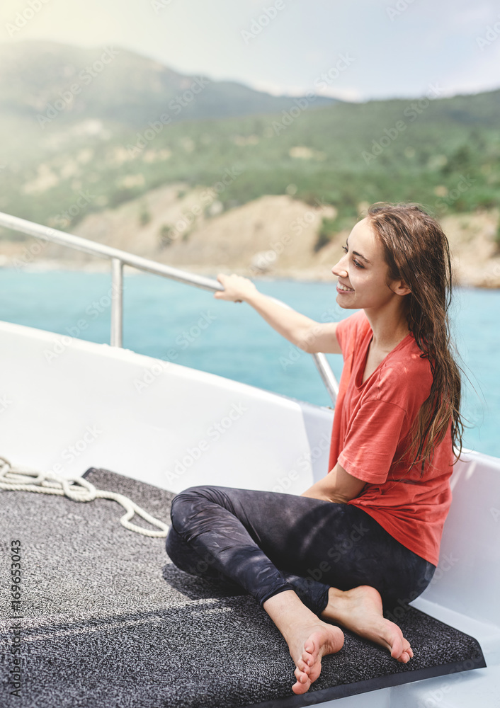 happy young smiling woman in the white boat on the cloudy sky background. woman wearing in a red t-shirt looks very happy. Caucasian female model