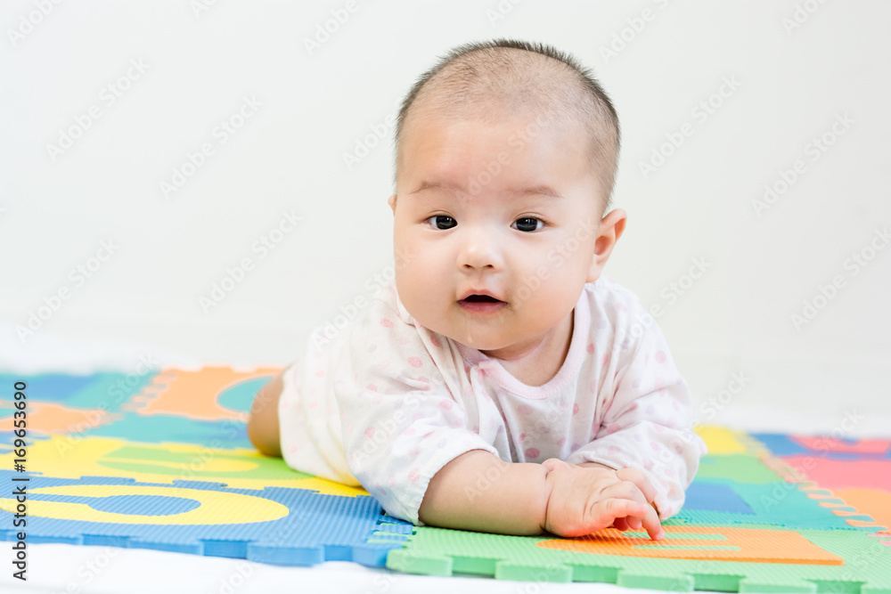 Portrait of adorable baby with saliva lying on the tummy on colorful eva foam, indoors Portrait of adorable baby with saliva lying on the tummy on colorful eva foam, indoors