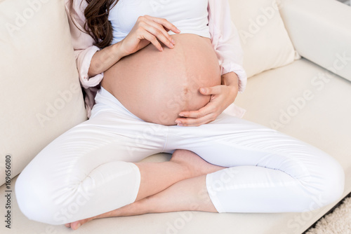 Pregnant woman touching her belly on couch