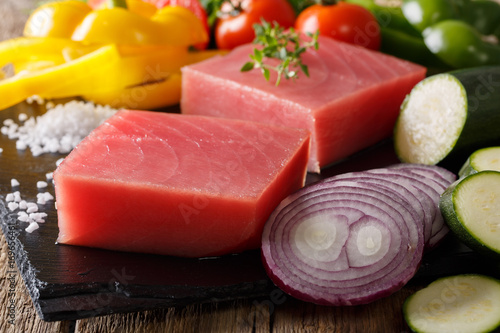 Fresh raw tuna steak with vegetable ingredients and spices close-up. horizontal