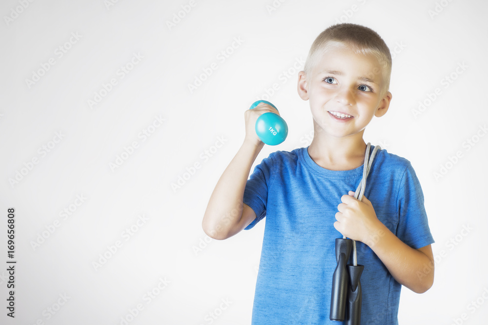Boy with skipping rope and dumbbell. Portrait happy, smiling boy holding a jump rope and dumbbell. The concept of a healthy lifestyle, sport or workout. Boy with skipping rope and dumbbell. Portrait happy, smiling boy holding a jump rope and dumbbell. The concept of a healthy lifestyle, sport or workout.