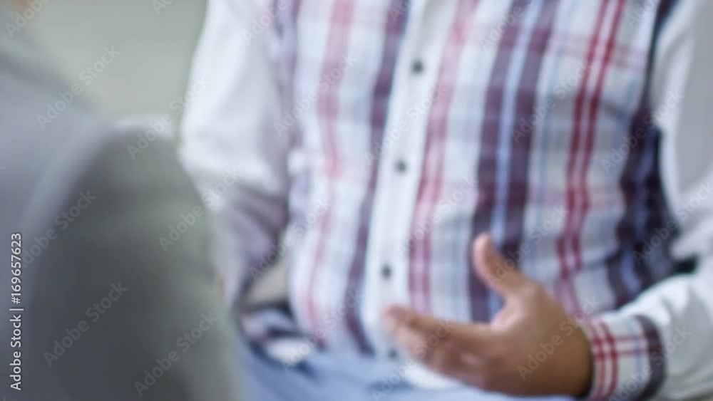 Tilt down of expressive Arab man with stubble gesturing while explaining something to unrecognizable woman with clipboard filling application form Tilt down of expressive Arab man with stubble gesturing while explaining something to unrecognizable woman with clipboard filling application form