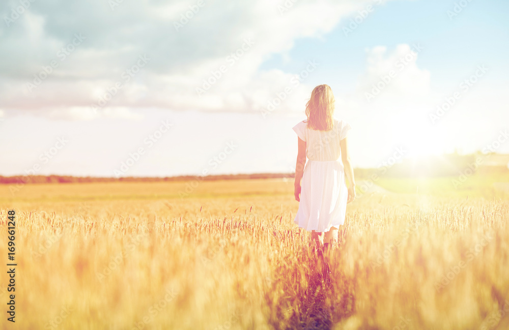 Obraz premium young woman in white dress walking along on field