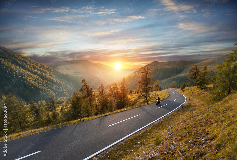 Obraz premium Kierowca motocykla jedzie na autostradzie alpejskiej. Fotografia plenerowa, krajobraz górski.