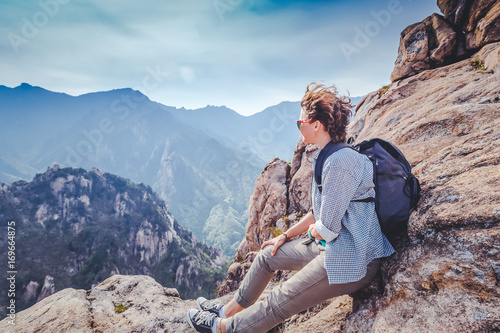 Happy young woman traveler in the mountains enjoying the view. Freedom, happiness, travel and vacations concept, outdoor activities