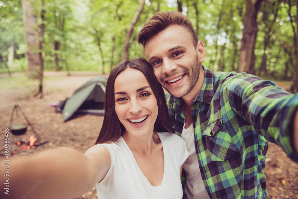 Close up of two young cheerful friends in the summer nice wood, embracing, posing for a selfie shot, that beautiful brunette lady is taking Close up of two young cheerful friends in the summer nice wood, embracing, posing for a selfie shot, that beautiful brunette lady is taking