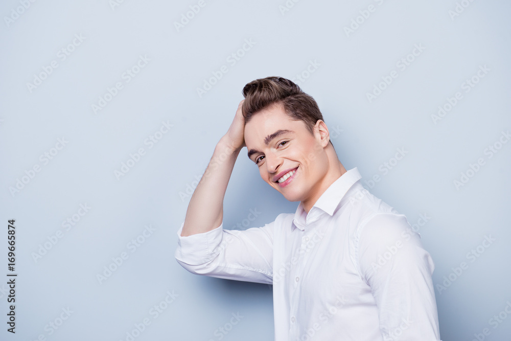 Handsome happy smiling man in white shirt touching his hair. Isolated on gray background. Handsome happy smiling man in white shirt touching his hair. Isolated on gray background.