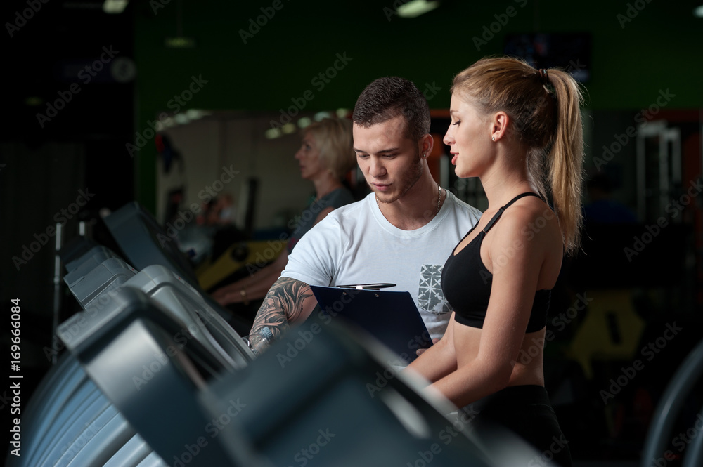 Smiling female working with personal coach in gym Smiling female working with personal coach in gym