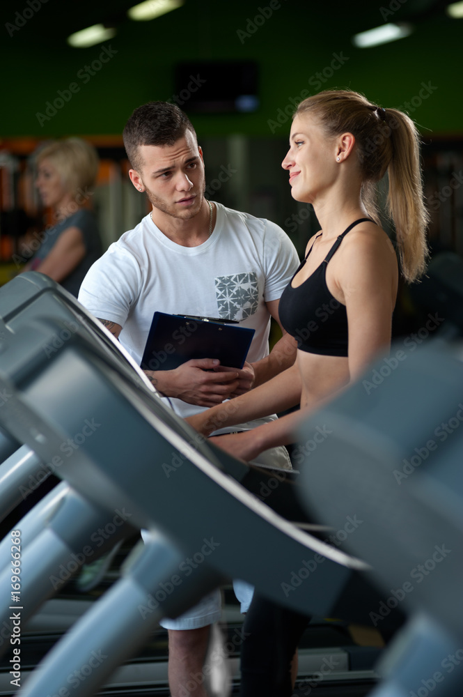 Smiling female working with personal coach in gym Smiling female working with personal coach in gym