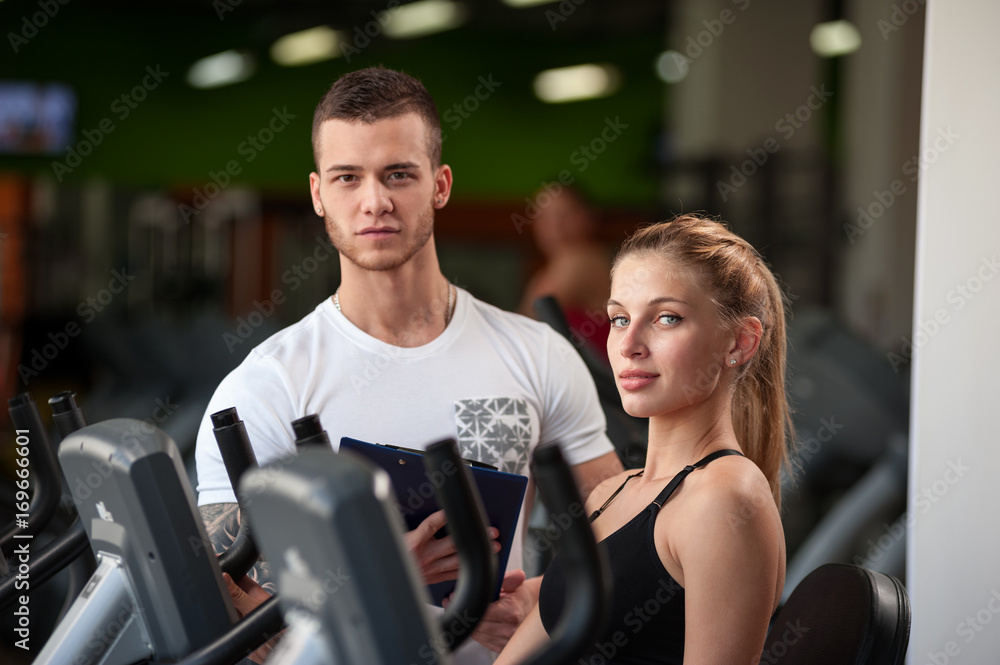 Personal trainer helping his female client in gym Personal trainer helping his female client in gym