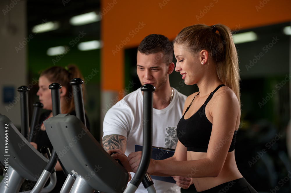 Blonde woman working out with fitness coach in gym Blonde woman working out with fitness coach in gym