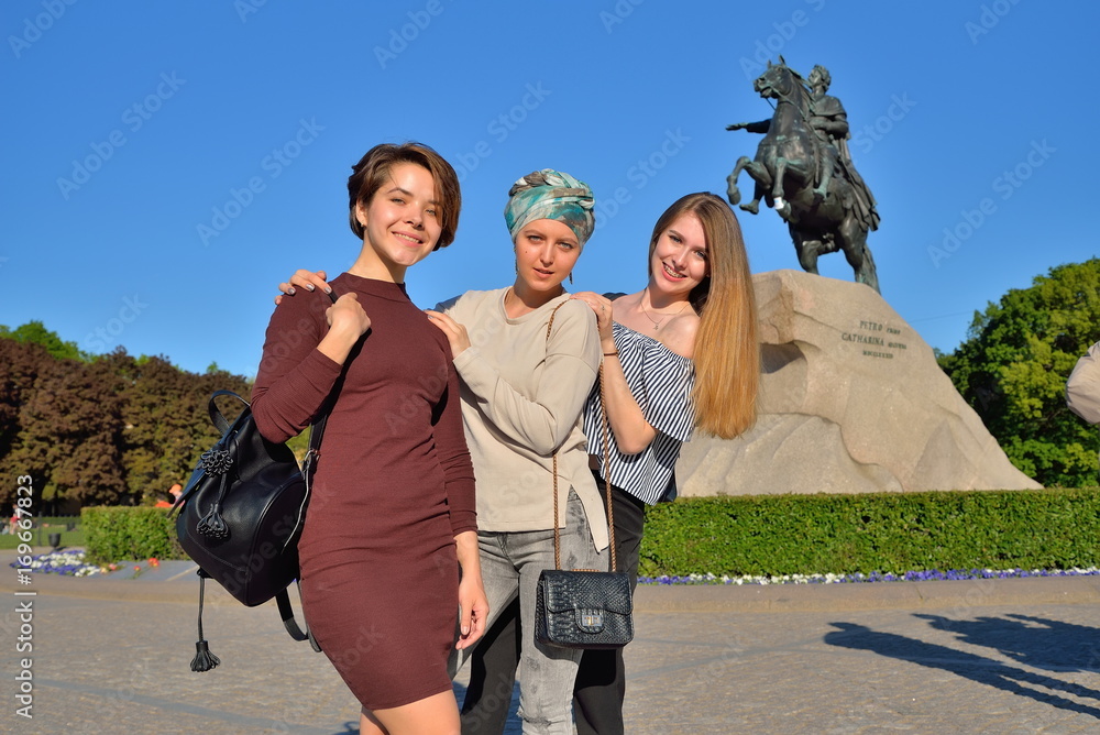 Obraz premium Three young girls are photographed on the background of the monument bronze Horseman in Saint-Petersburg