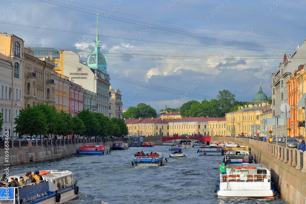 Tourist boats floating on the Moika river from red bridge in Saint-Petersburg