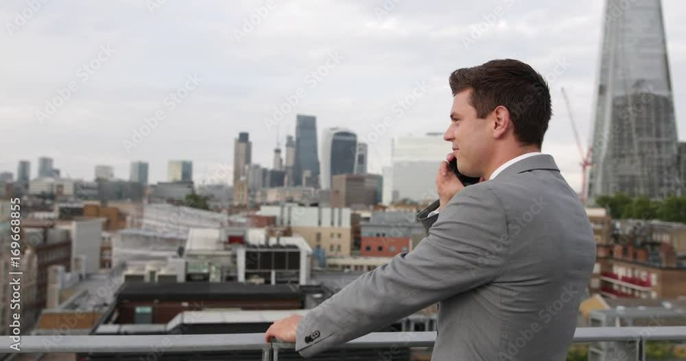 Businessman using smartphone looking out at London city skyline Businessman using smartphone looking out at London city skyline