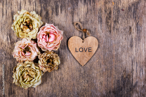 Dry withered roses and a heart on an old wooden background. Copy space