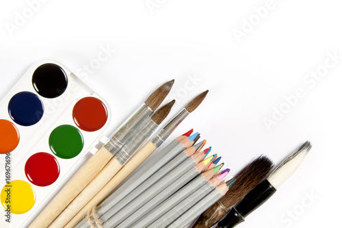 Set of colored pencils, paint brushes and watercolor paint-box isolated on the white.