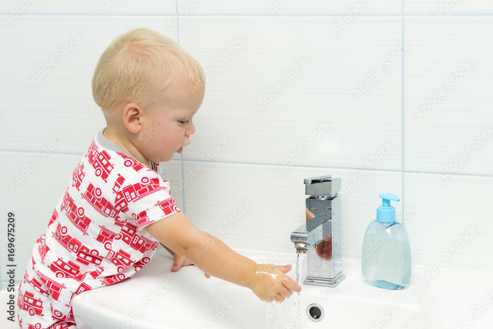 Close-up portrait of adorable white Caucasian boy toddler one year old washing hands in bathroom and looking surprised excited, playing with water Close-up portrait of adorable white Caucasian boy toddler one year old washing hands in bathroom and looking surprised excited, playing with water