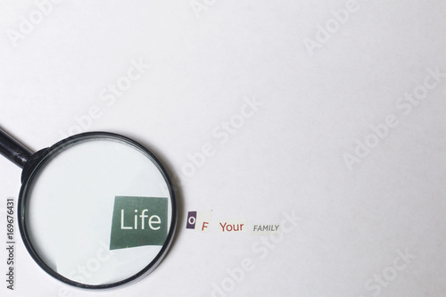 Criminal activity. Preparation of a letter with threats. Letters cut from different editions are pasted onto a white sheet of paper. Above the inscription lies a magnifying glass. photo