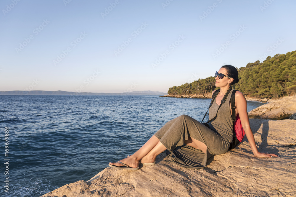Young woman photographer on a rocky seashore on evening.