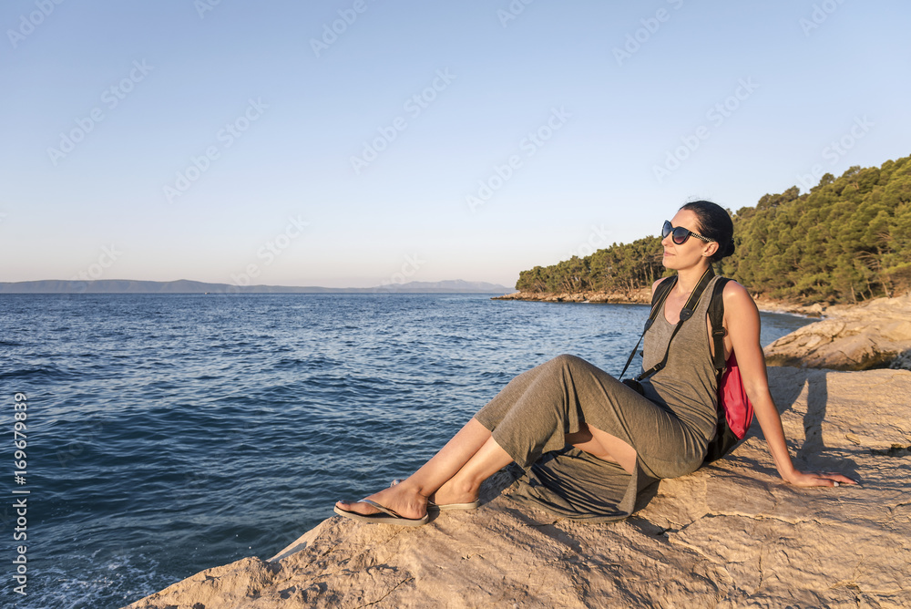 Young woman photographer on a rocky seashore on evening. Young woman photographer on a rocky seashore on evening.