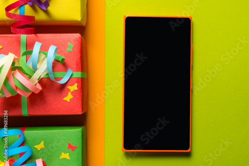 Gift boxes and smart phone on colorful background