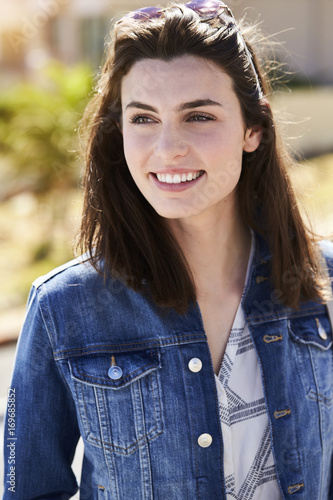 Happy young woman in brunette and denim, looking away