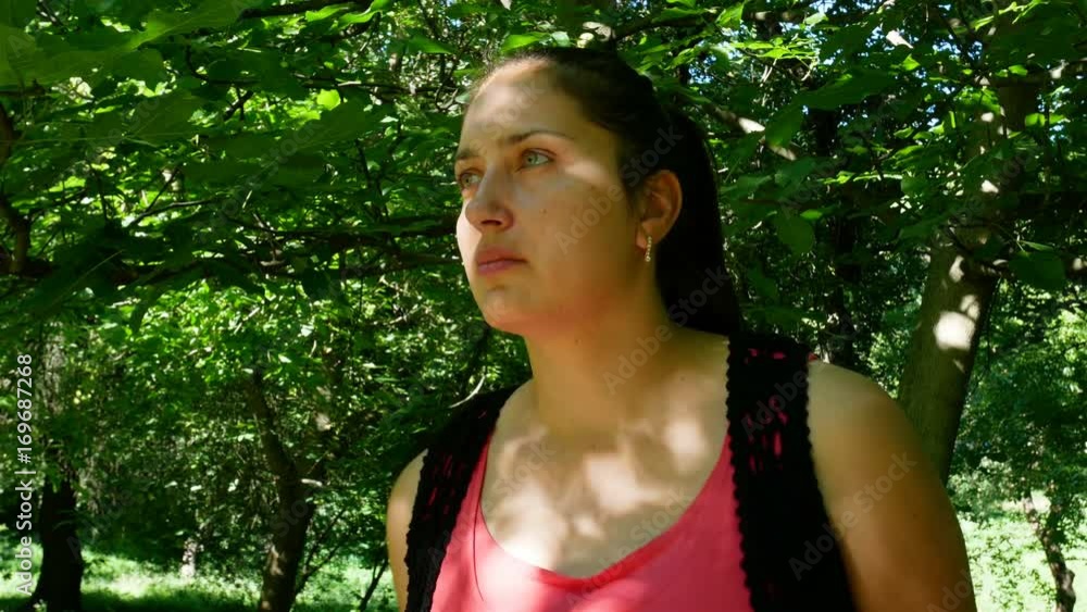 Calm Brunette. Young beautiful woman in a summer dress posing against spring park outdoors, Looks away in the expectation of his lover