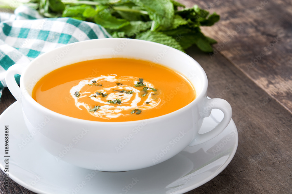 Pumpkin soup in white bowl on wooden table
Pumpkin soup in white bowl on wooden table