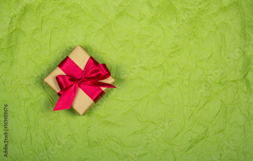Gift box with satin bow on a pale paper background. Backgrounds and textures. Copy space