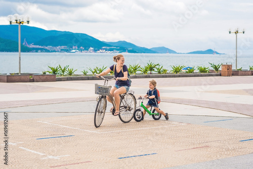 Happy family is riding bikes outdoors and smiling. Mom on a bike and son on a balancebike photo