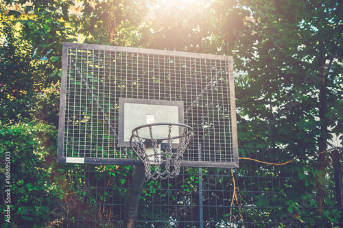 steel basketball basket with trees in the background and warm sunlight