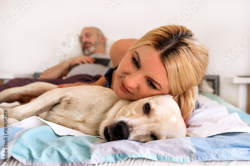 Woman with dogs at home. Handsome woman resting and sleeping with her dog in bed in the bedroom. Owner and dog sleeping. Pet concept. Yellow labrador retriever relax, lonely woman and her best friend.