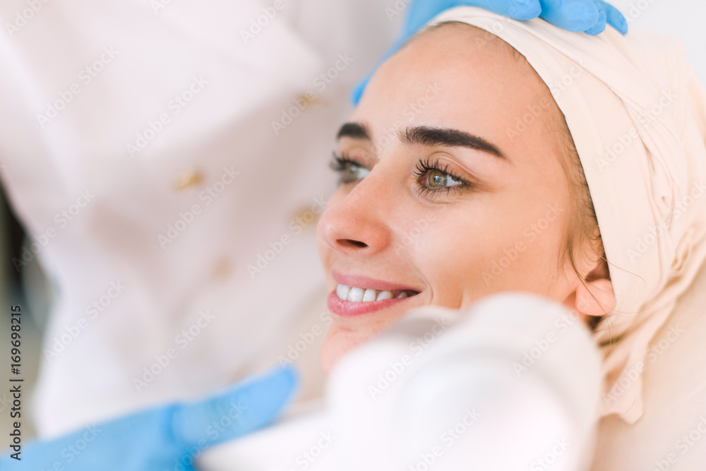Young healthy woman with good skin doing cosmetic procedures in spa clinic