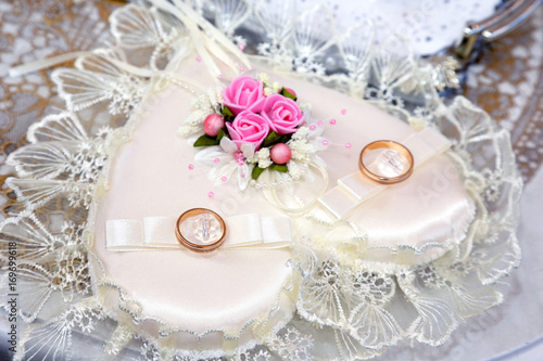 Wedding rings lie on a beautiful embellished rhinestone pillow photo