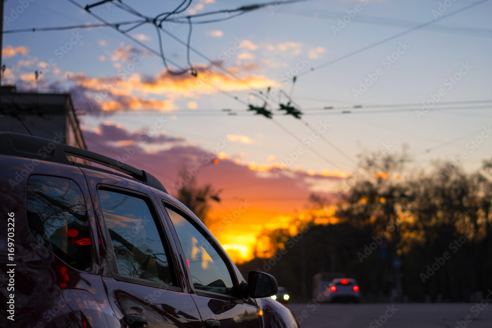 Epic sunset in the city, lights reflections on the car with wires on blurred background.