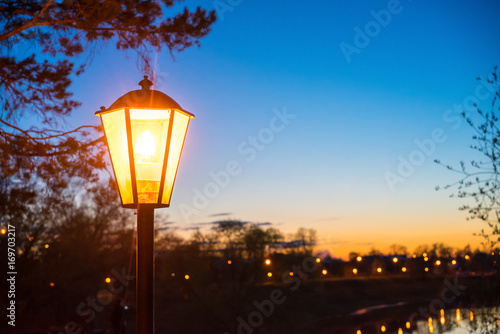 Retro street lamp in the city park at summer sunset. Copy space for description.