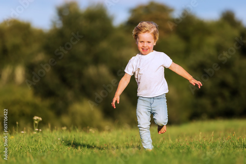 cute young boy runs over a meadow