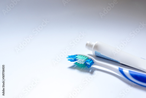  Toothbrush with toothpaste next to a tube of toothpaste against white background