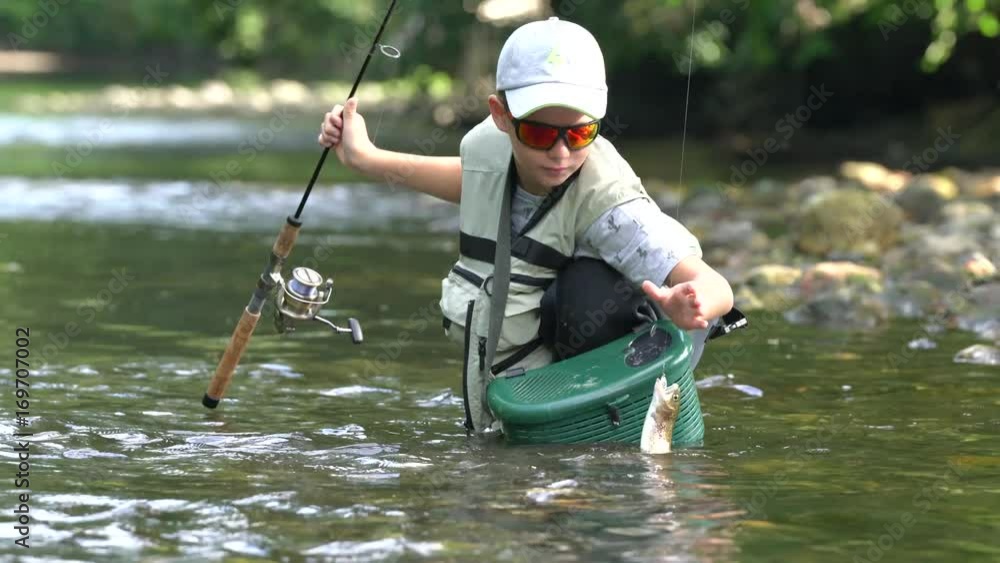 Young boy catching rainbow trout in river Young boy catching rainbow trout in river