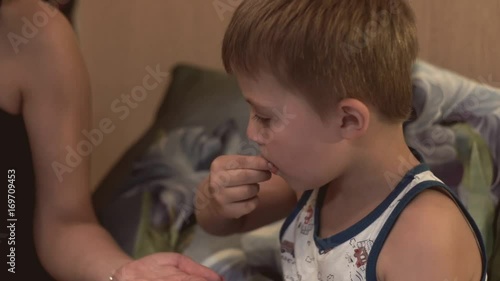 Little boy takes tablet and drinks water. Sick boy takes tablet and drinks water