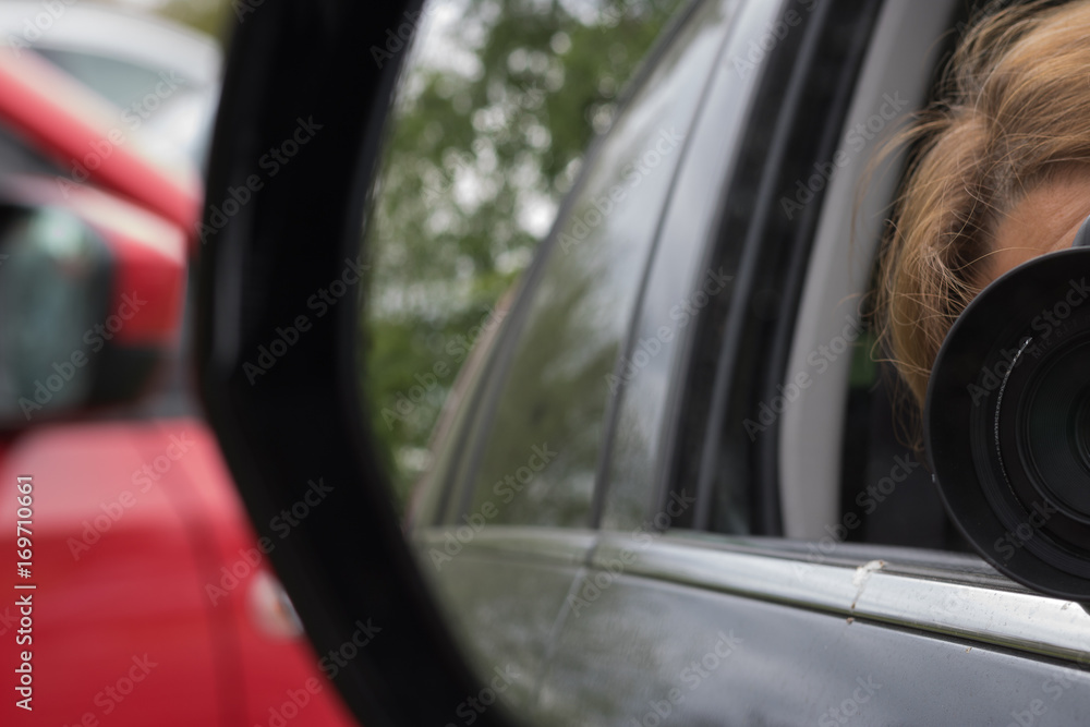 A photographer takes pictures from a car window. View through a car's side mirror.