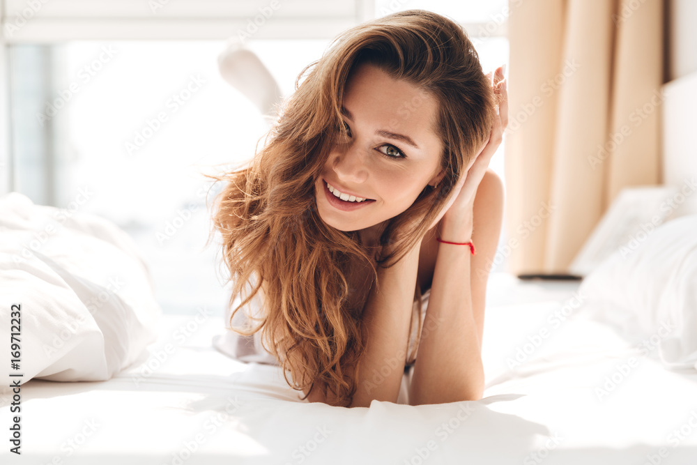 Portrait of brunette woman lying in bed and looking camera Portrait of brunette woman lying in bed and looking camera
