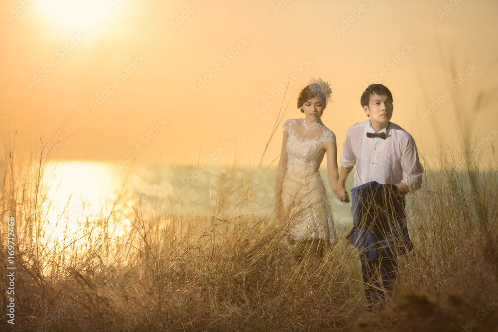 Asian couple with pre wedding sceen outdoor dry meadow on the hill and the  sea at sunset is falling background.,thai lover Stock Photo | Adobe Stock