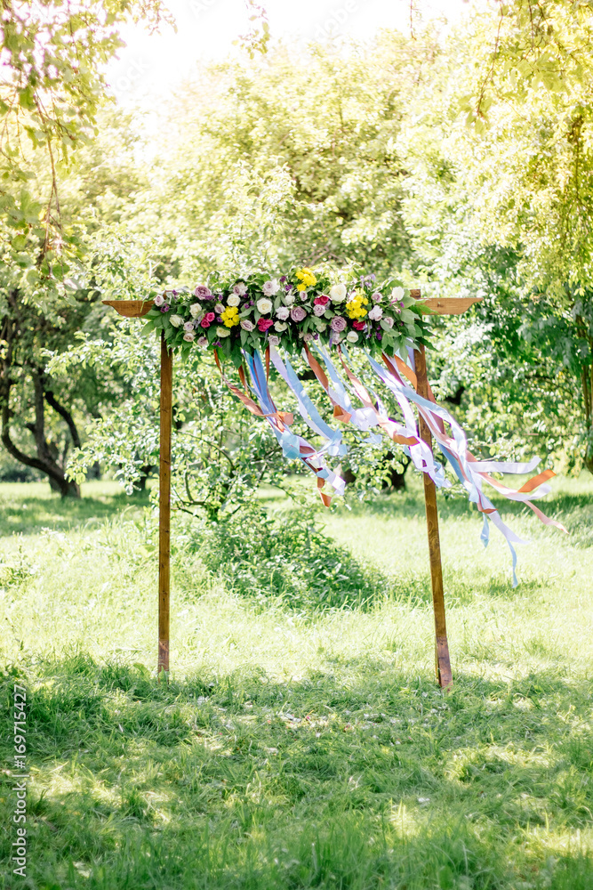 Beautiful wedding arch with flowers on forest at summer day.
