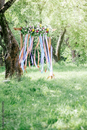 Beautiful wedding arch with flowers on forest at summer day.